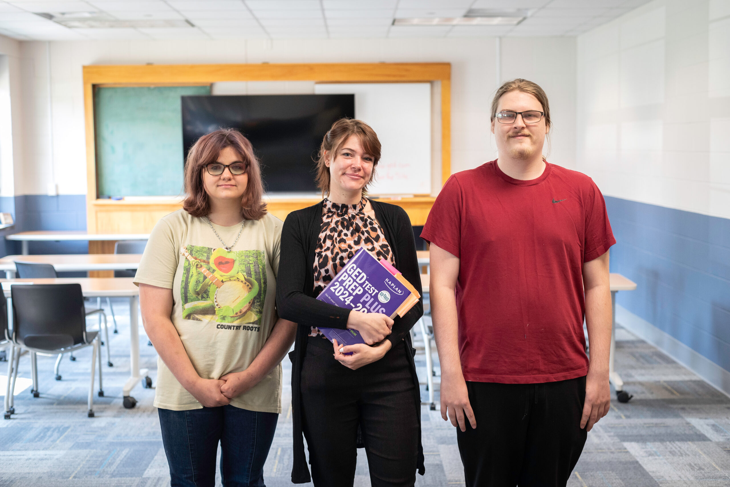 Three adult education students, one with a GED prep book